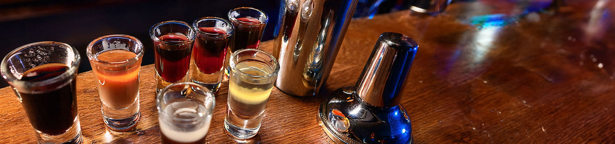 Bitter Likör und weitere Likörsorten in Shotgläsern auf einem Holztisch
