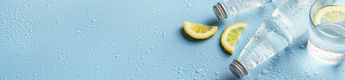 Heilwasser in einer Wasserflasche und einem Glas mit Zitronenscheibe