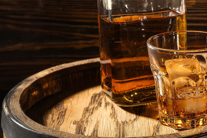 Whiskyglas und Whiskyflasche mit Blended Whisky auf einem Whiskyfass