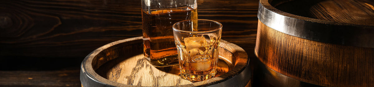 Whiskyglas und Whiskyflasche mit Bourbon Whiskey auf einem Whiskyfass