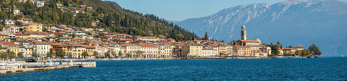 Italienischer Wein aus der Lombardei – Blick auf Stadt am See, Berge und Weinreben im Hintergrund