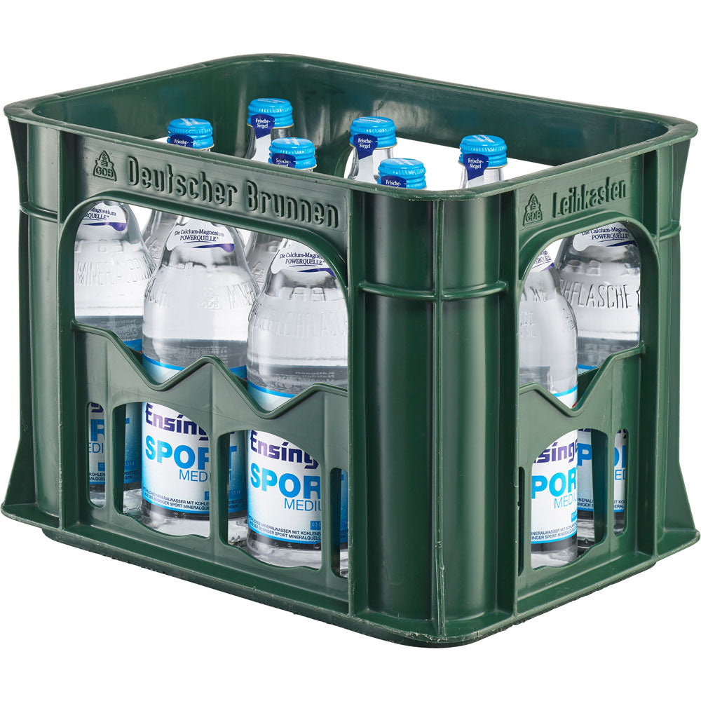 Eine grüne Kiste mit zwölf 0,5-Liter-Flaschen Ensinger Sport Medium Mehrweg Mineralwasser mit blauem und weißem Etikett, das für seinen Kalziumgehalt und seine geringe Kohlensäure geschätzt wird.