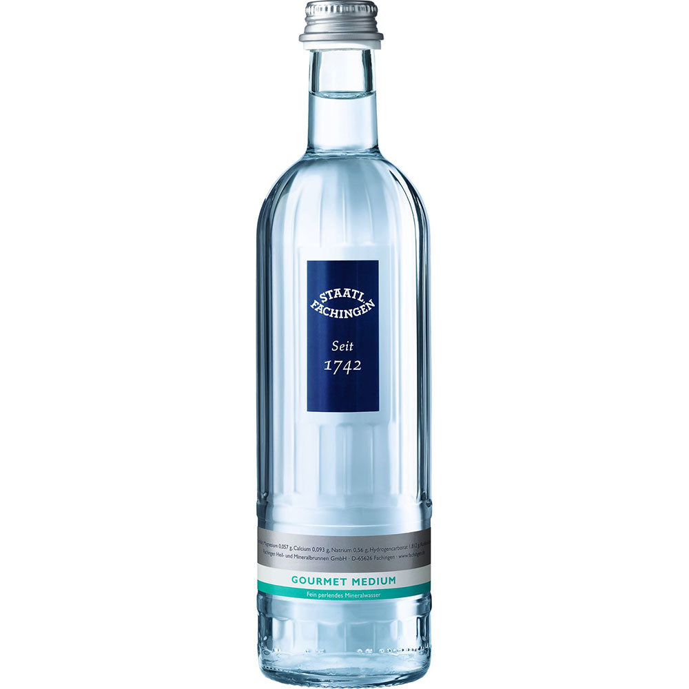 Eine Klarglasflasche von Staatl. Fachingen Gourmet Medium 0,5L (MEHRWEG), bekannt für seinen erfrischenden Geschmack und hohen Hydrogencarbonatgehalt, mit blauem und silbernem Etikett.