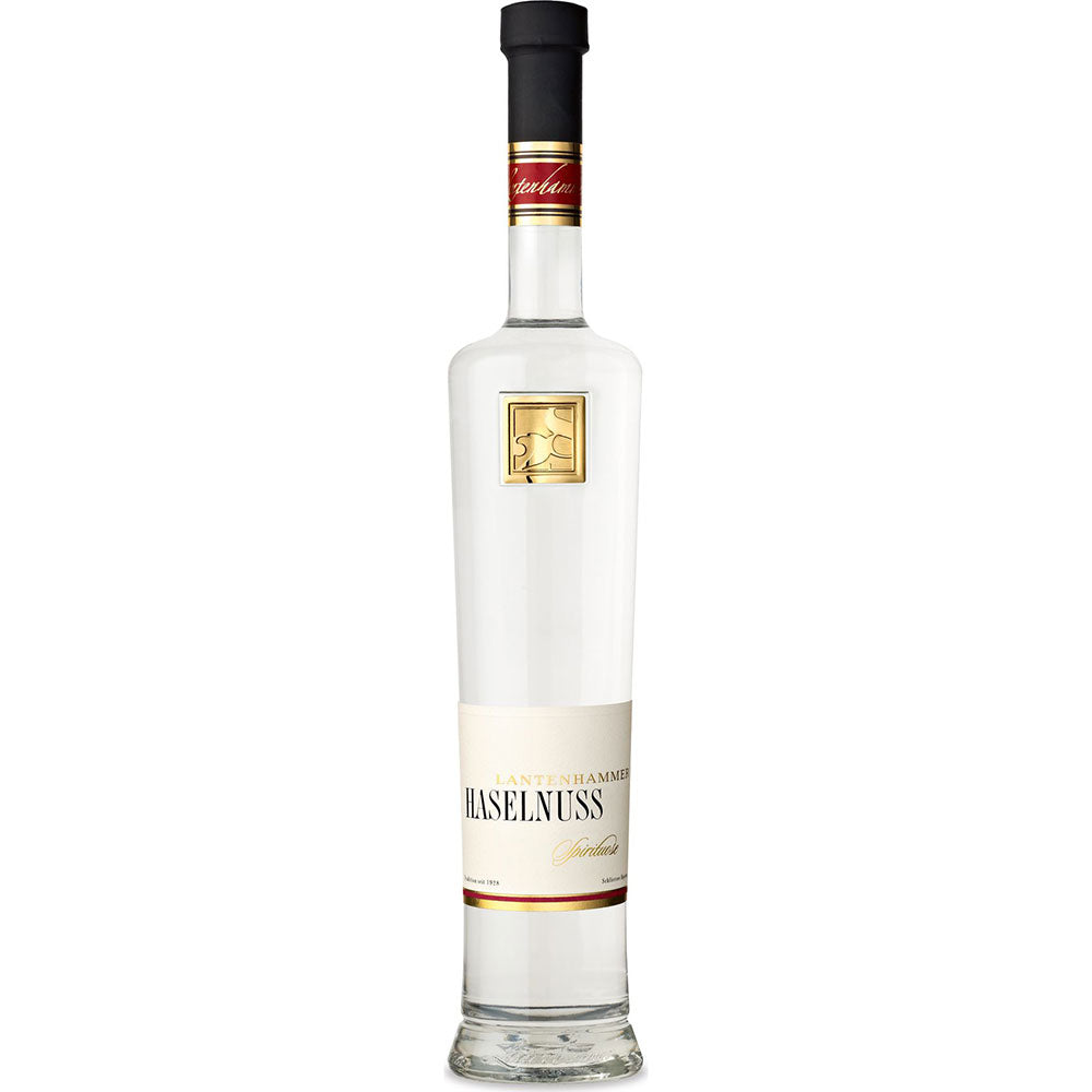 Lantenhammer Haselnussspirituose 42% 0,5 Liter kommt in einer hohen Klarglasflasche mit einem weiß-goldenen Etikett, das die traditionelle Nussbrand-Handwerkskunst der Marke unterstreicht.