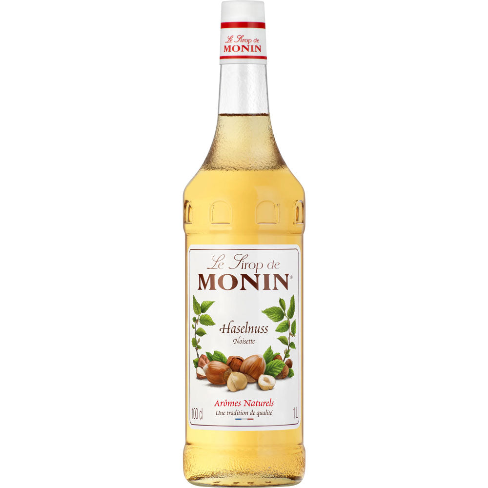 Eine 1-Liter-Flasche Monin Haselnuss Sirup von Monin, mit einem Etikett mit Haselnüssen und Blättern auf weißem Hintergrund.