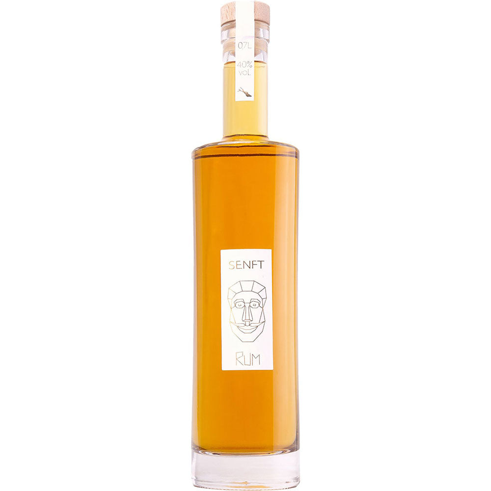 Senft Bodensee Rum 40% 0,7 Liter: Elegante hohe Glasflasche mit Korkverschluss und minimalistischem, weißem Etikett mit einer Gesichtsillustration, die die deutsche Handwerkskunst von Senft hervorhebt, und einem raffinierten Jamaica Wood Finish.