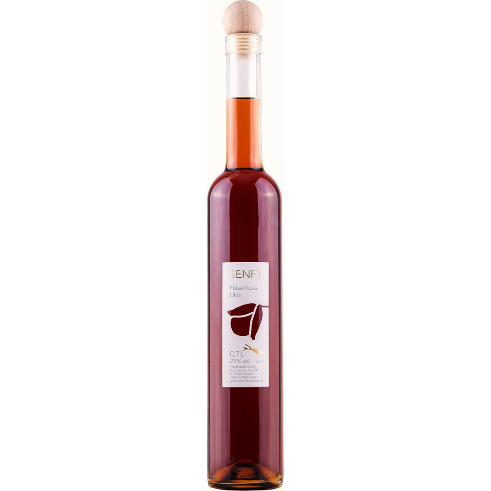 Senft Haselnuss Likör 23% (0,5L) wird in einer hohen, schlanken Flasche mit Holzverschluss und weißem, vom Bodensee inspiriertem Etikett geliefert, die von Senft hergestellt wird.