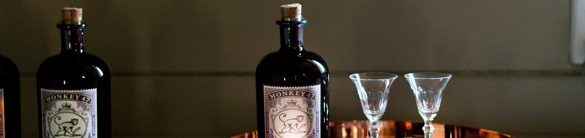 Zwei Flaschen Monkey 47 Gin mit Korkverschluss, servierbereit mit edlen Gläsern auf Kupfertablett