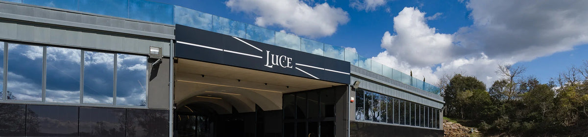 Ein modernes Gebäude mit Glasfenstern und einem Schild mit der Aufschrift „LUCE“ vor einem blauen Himmel mit Wolken.