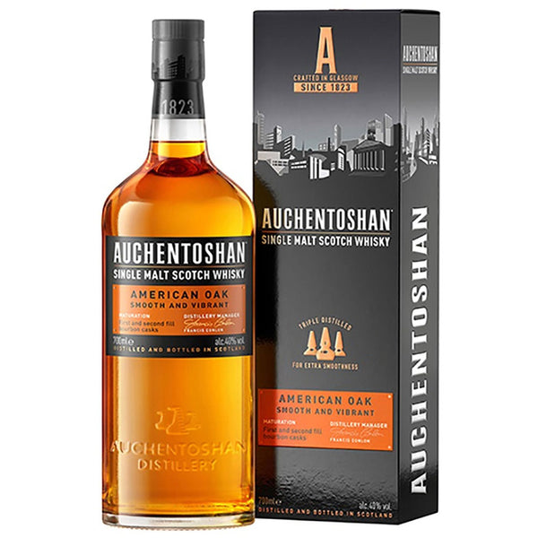 Eine Flasche Auchentoshan American Oak Single Malt Scotch Whisky 40% 0,7 Liter von Auchentoshan wird neben der stilvollen schwarz-orangenen Schachtel präsentiert.