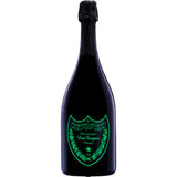 Eine dunkle Champagnerflasche Dom Pérignon Vintage Luminous Label 0,75 Liter mit einem leuchtend grünen Etikett hebt sich vor einem weißen Hintergrund ab.