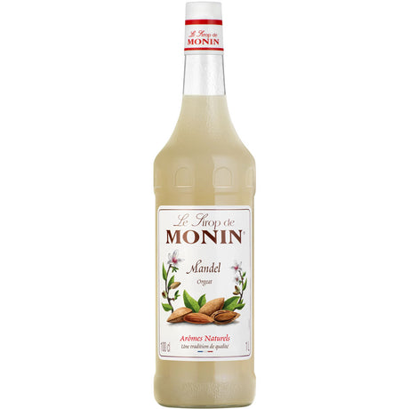 Eine 1-Liter-Flasche Monin Mandel Sirup von Monin mit einem weißen Etikett, auf dem Mandeln und Mandelblüten abgebildet sind.