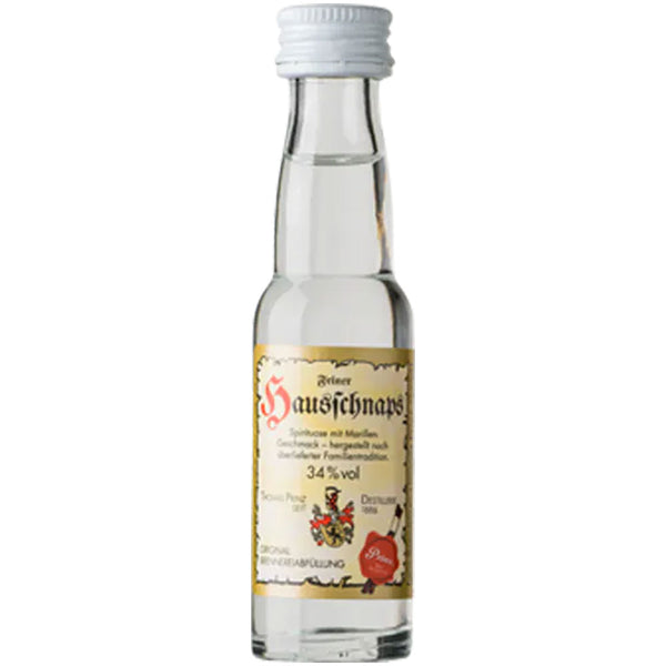 Eine kleine Klarglasflasche mit der Aufschrift "Prinz Hausschnaps Marille 34% 0,02 Liter" der Feinbrennerei Thomas Prinz, gefüllt mit klarem Schnaps und verschlossen mit einem weißen Deckel.