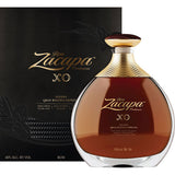 Der Ron Zacapa Rum Centenario XO 25 Jahre (40%, 0,7l) mit goldenen Akzenten steht vor seiner edlen schwarz-goldenen Box.
